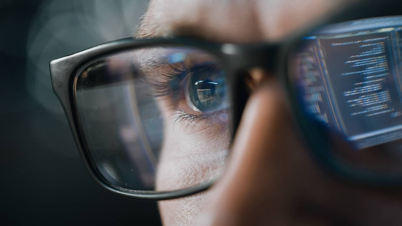 software programmer with code reflected in glasses